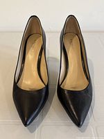 Front view of COACH black leather women's heels, showing pointed toes and smooth leather finish.