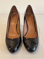 Front view of pair of COACH women's black patent leather high heel pumps size 9 showing round toes and glossy finish.