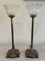 Pair of antique style table lamps with brass bases and clear glass shades on white surface
