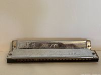 Front view of one vintage Hero harmonica showing the metal cover plate with engraving and moderate surface wear.