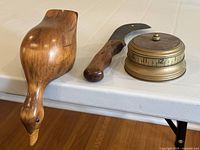 All three items: wooden duck decoy, antique sickle, and brass timer placed together for size and condition reference.