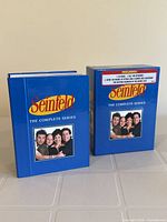 Front view of the Seinfeld Complete Series DVD box set showing the blue box case with main characters and series title.