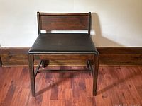 Front view of the wooden vanity bench showing the black vinyl cushioned seat and wooden backrest