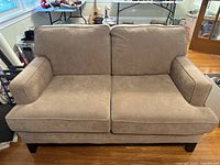 Front view of taupe two seater sofa showing fabric cushions and armrests.