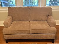 Front view of the two-seater taupe fabric sofa showing two seat cushions, two back cushions, and wooden legs.
