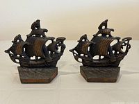 Pair of cast iron pirate ship bookends shown side by side with visible detail of ship sails, masts, and anchors.