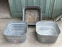 Three galvanized steel rectangular wash buckets with some rust, one with a Eureka brand label on front.