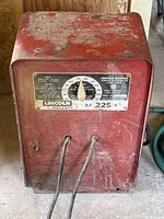 Front view of red Lincoln Electric AC-225-S arc/stick welder unit showing control dial and cable inputs