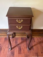 Front view of vintage mahogany side table showing two drawers with brass pulls and curved cabriole legs.