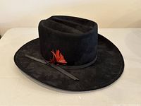 Front side view of black felt cowboy hat with decorative feather and ribbon.