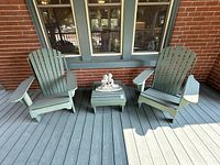 Two matching painted light green wooden Adirondack chairs on porch deck