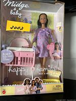 Front view of Midge doll and baby in box with crib/table/cradle accessory and branding visible.