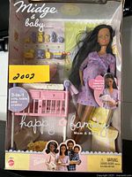 Front view of boxed Midge and baby doll set with visible 3-in-1 furniture crib/table/cradle and baby accessories.