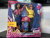 Front view of boxed 2016 Mattel Barbie President and Vice President doll set, showing two dolls and podium with 'First All Female Ticket!' banner.