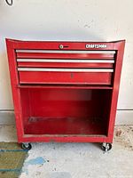 Front view of red Craftsman rolling tool chest showing two drawers with silver handles and large open bottom compartment.
