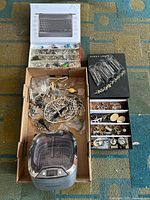 Overall shot of the jewelry lot including assorted jewelry pieces displayed in trays and boxes, alongside the Magnasonic Ultrasonic Cleaner at the bottom.