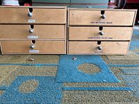 Closed view of six wooden storage boxes labeled with contents like optical, wire/zip ties, nails, nuts/bolts, wood screws