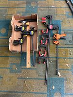 Overview of the collection showing ten clamps with varying sizes and colors on a patterned rug.