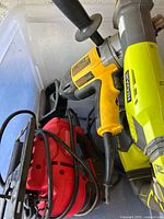DeWalt drill, Ryobi jigsaw, and Craftsman air compressor inside plastic storage case