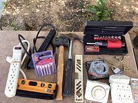 Photo showing the full set of items including hammers, level, screwdriver set, batteries, wire with lock, hooks, power strip, timer, lock box, and duct tape.