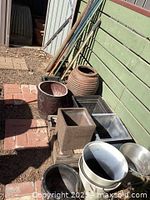 Overview of garden pots and garden poles leaning against fence outside