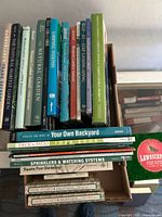 Photo showing 22 gardening and landscaping books stacked vertically and horizontally, titles include The Natural Habitat Garden, The Natural Garden, Western Garden Annuals, Step-by-Step Landscaping, Sprinklers & Watering Systems, and others.