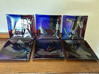 All six square plates displayed side by side on wooden surface