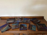 Top view of nine unique glass art plates on a wooden table, showing color and size variation.