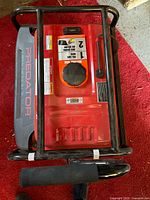 Top view showing red fuel tank, fuel cap, warning labels and black steel roll cage