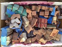 Top view of box with many terracotta pot stands of various shapes and sizes including blue painted and natural terracotta ones.