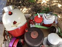 Box of vintage kitchen and picnic items including The American Beauty Picnic Jug and Juice King appliance, various small accessories scattered around.