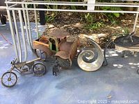 Lot displayed with vintage truck plant holder, motorcycle sculpture, small animal figure, abstract metal shell, and sundial metal table.