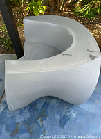 Gray plastic easy chair taken from a top-side angle showing the armrest and curved ergonomic design