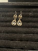 Front view of both gold filled earrings hanging on a black textured display board, showing decorative scrollwork design and hook ear wires.