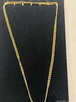 Full view of the gold chain laid out straight showing entire length and clasp end.