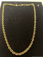 Full view of thick gold filled chain necklace arranged on black background