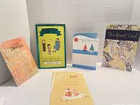 Five Father's Day greeting cards displayed standing on a white surface with a blank textured backdrop. Cards include a pink orange 'From Daughter' card, green 'Great Dad's Unusual Advice' card, blue and white sailboat card, floral 'To a Great Dad' card, and yellow 'Dad' card with fox design.