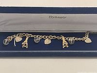 Charm bracelet with gold plated links and charms displayed inside a Dynasty box, showing charms including clear beads, rhinestone hearts, and giraffes.