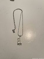 Full view of the necklace with the chain and pendant showing the number '21' and the word 'PLUS'.