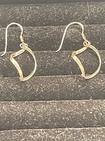 Pair of .925 sterling silver earrings with angular open loop design on black textured display.