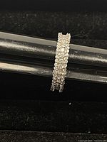 Close-up image of a sterling silver ring featuring two rows of clear Swarovski crystals on the band, displayed on a black ring holder.
