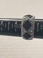 Front angle view showing the ring's silver band with black diamond-shaped Swarovski crystals and clear crystals around them.