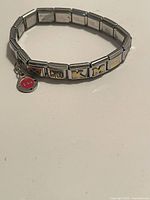 Silver boxed link charm bracelet featuring multiple close-ups views showing letter charms and symbol charms, including heart, teddy bear and smiley face dangle.