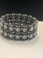 Five-row elastic bracelet with round clear crystals and black spacer beads on silver-tone metal.