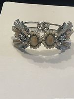Front view of bracelet showing oval cream-colored stones and clear rhinestone accents on silver-tone metal.