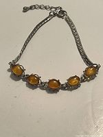 Front view of the silver amber bracelet showing five oval cabochon amber stones set in decorative silver mounts on a silver curb chain.