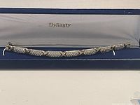 Image of two tone bracelet inside Dynasty branded box showing the full length and clasp.