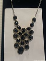 Full view of vintage statement necklace with black faceted gems arranged in a bib style on gold-tone chain.