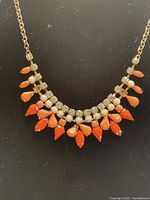 Full view of vintage burlesque style necklace with crystals and coral pendants on black background