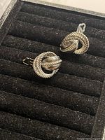 Close up of vintage silver tone clip on earrings showing rope twist circular design and clip mechanism.